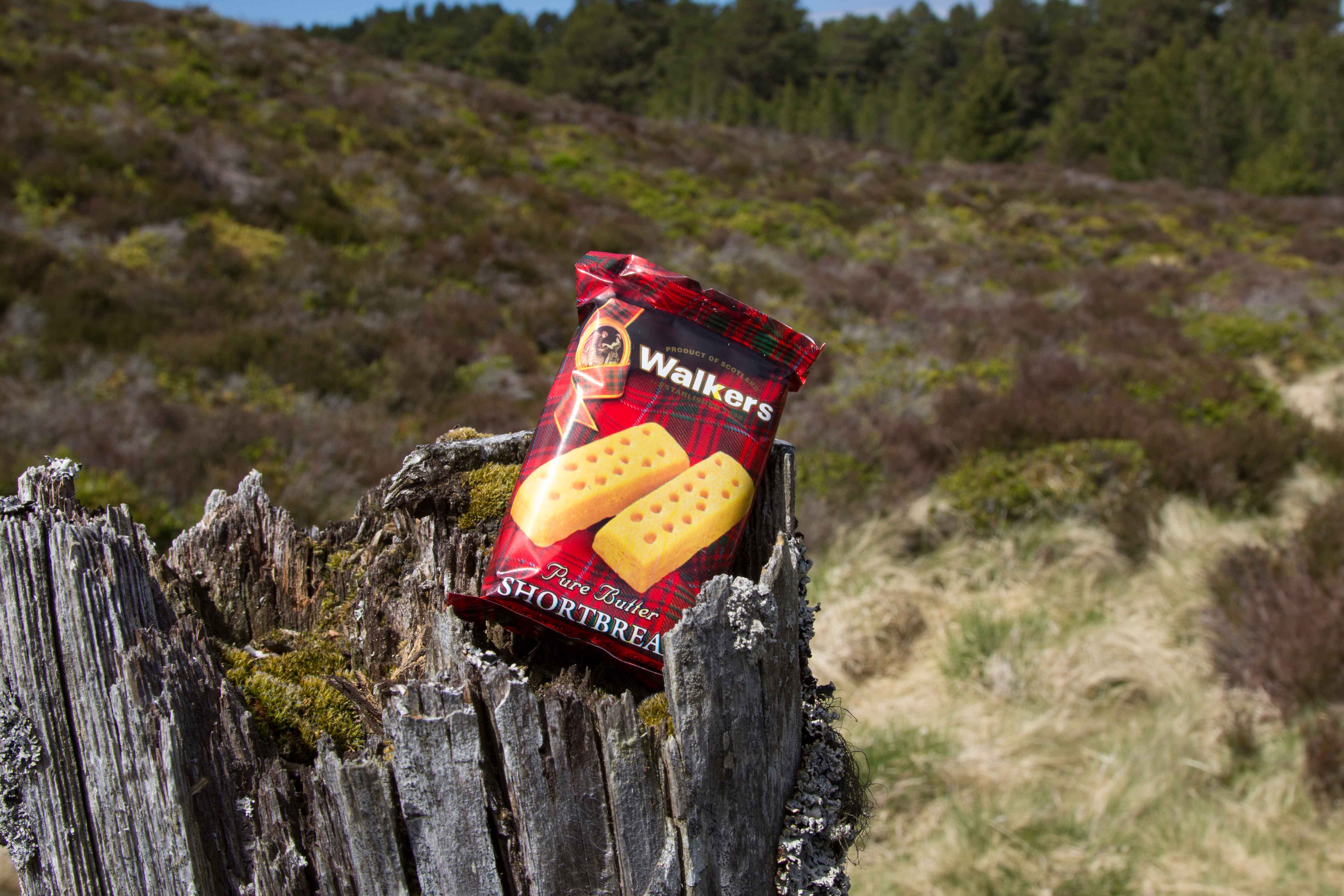Walkers Shortbread snackpack lying on bark within scottish landscape