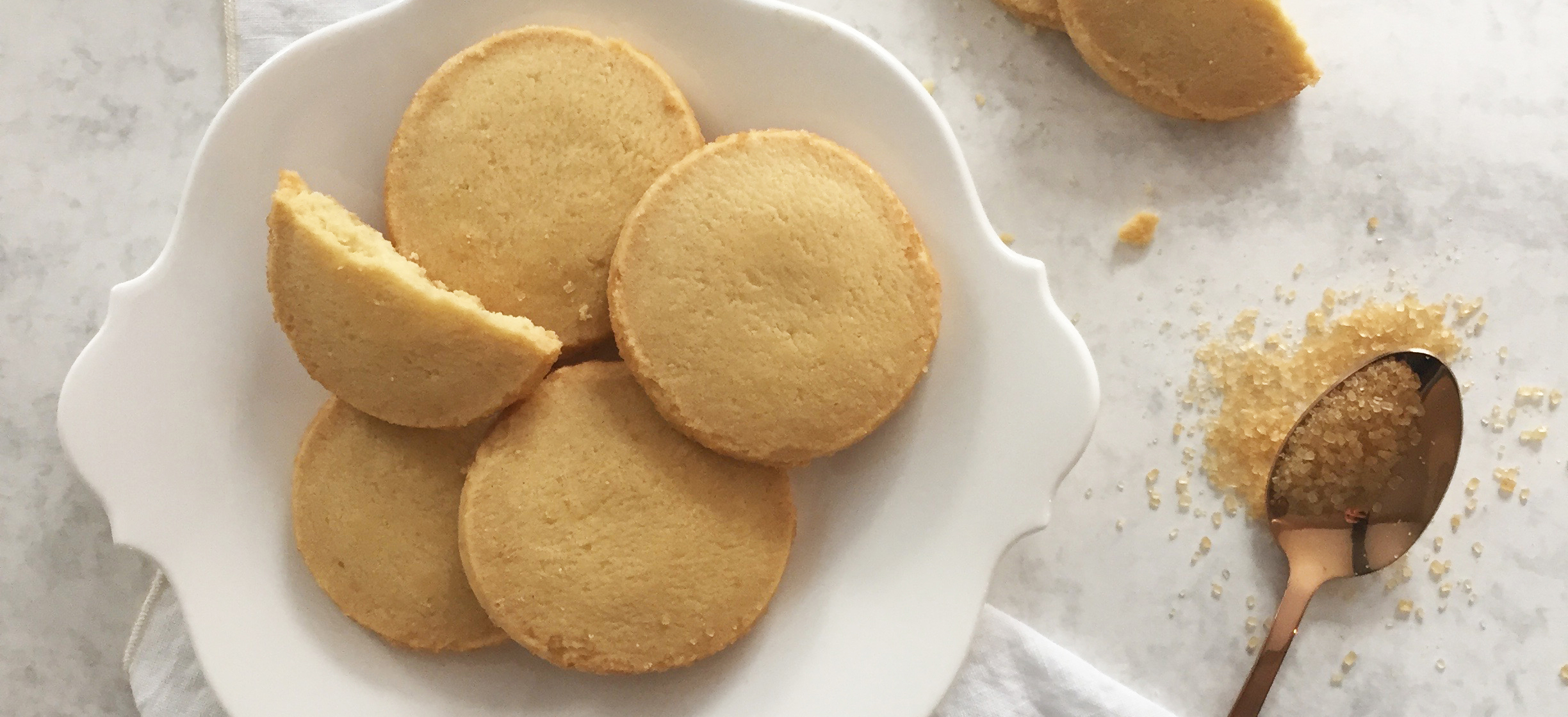 Walkers Shortbread Highlanders on a white plate with a spoon of brown sugar